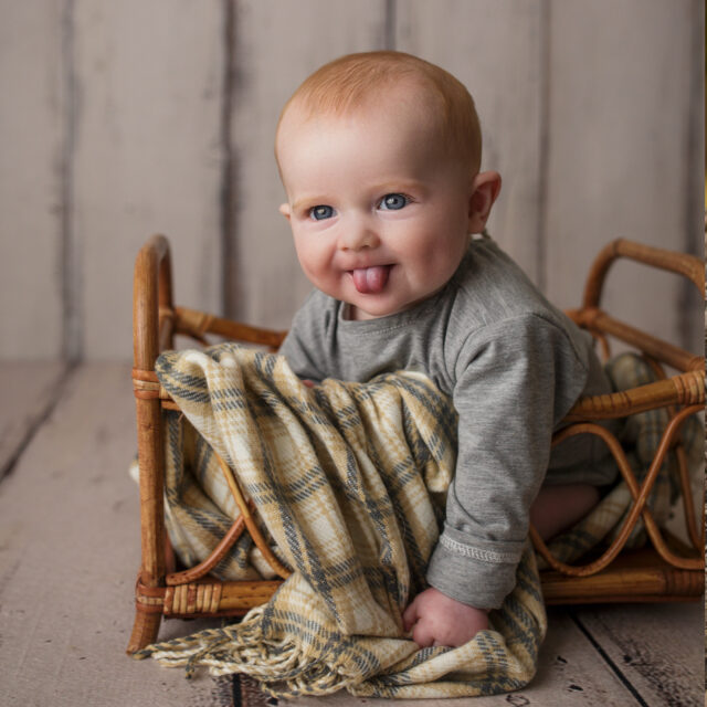 perryville newborn photographer, Perryville cake smash photographer, Cape Girardeau newborn photographer, baby sitting in basket, baby smiling, red head, wood floor
