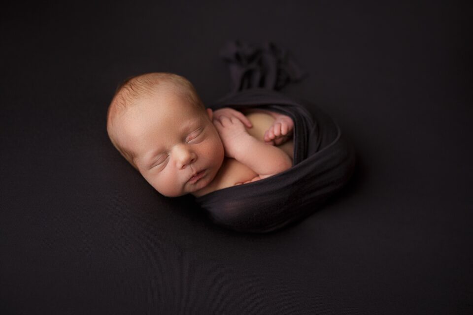 Perryville newborn photographer, Cape Girardeau newborn photographer, baby on black blanket, studio photoshoot, baby boy sleeping