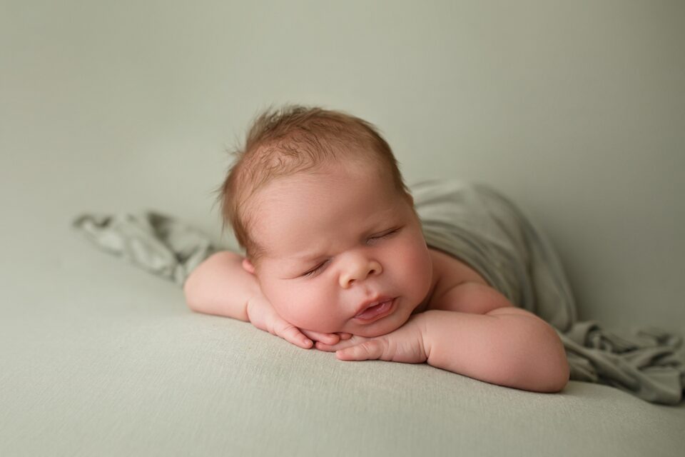 Perryville newborn photographer, Cape Girardeau newborn photographer, baby laying on green blanket, baby boy, photoshoot, newborn baby