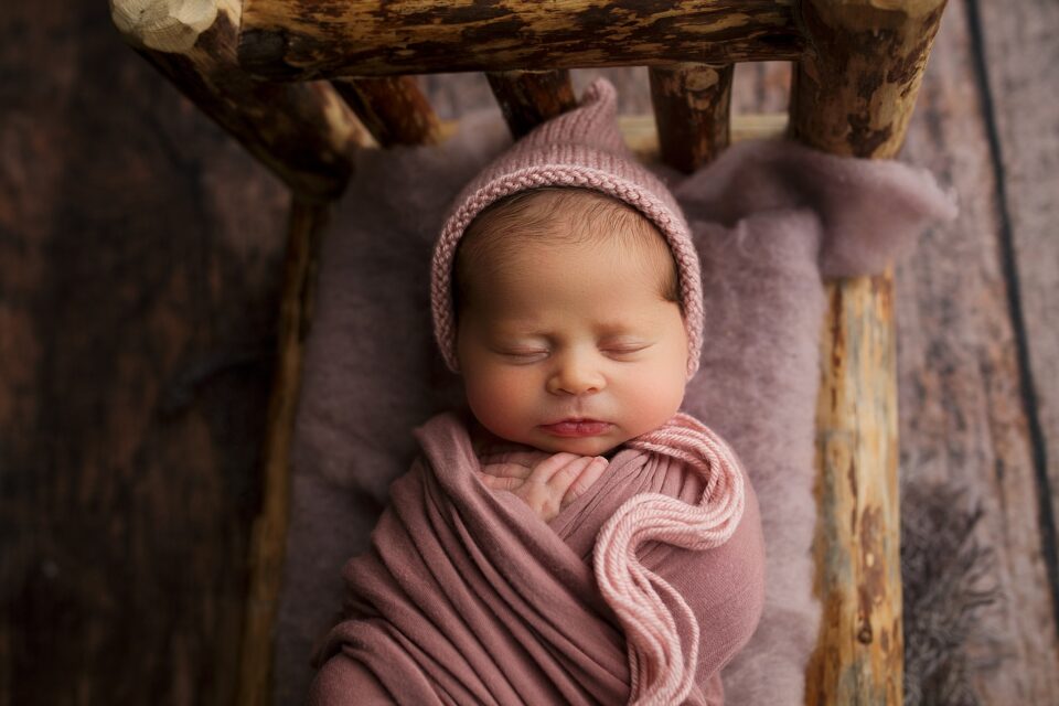 Cape Girardeau newborn photographer, baby on bed, pink newborn, baby wearing pink hat, newborn girl photoshoot