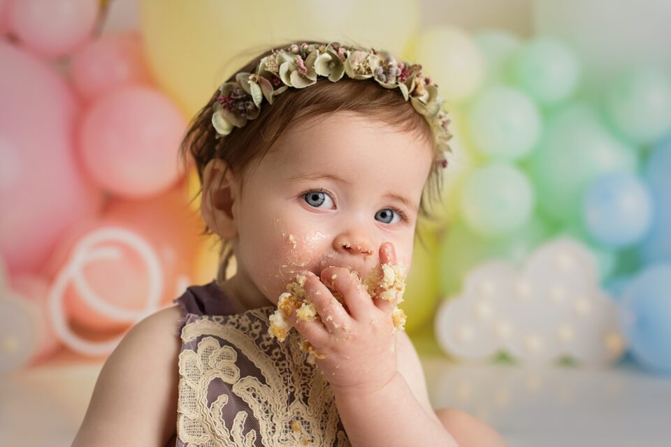 Cape Girardeau newborn photographer, perryville newborn photographer, baby eating cake, cake smash photographer, blue eyes, rainbow balloon cake smash setup