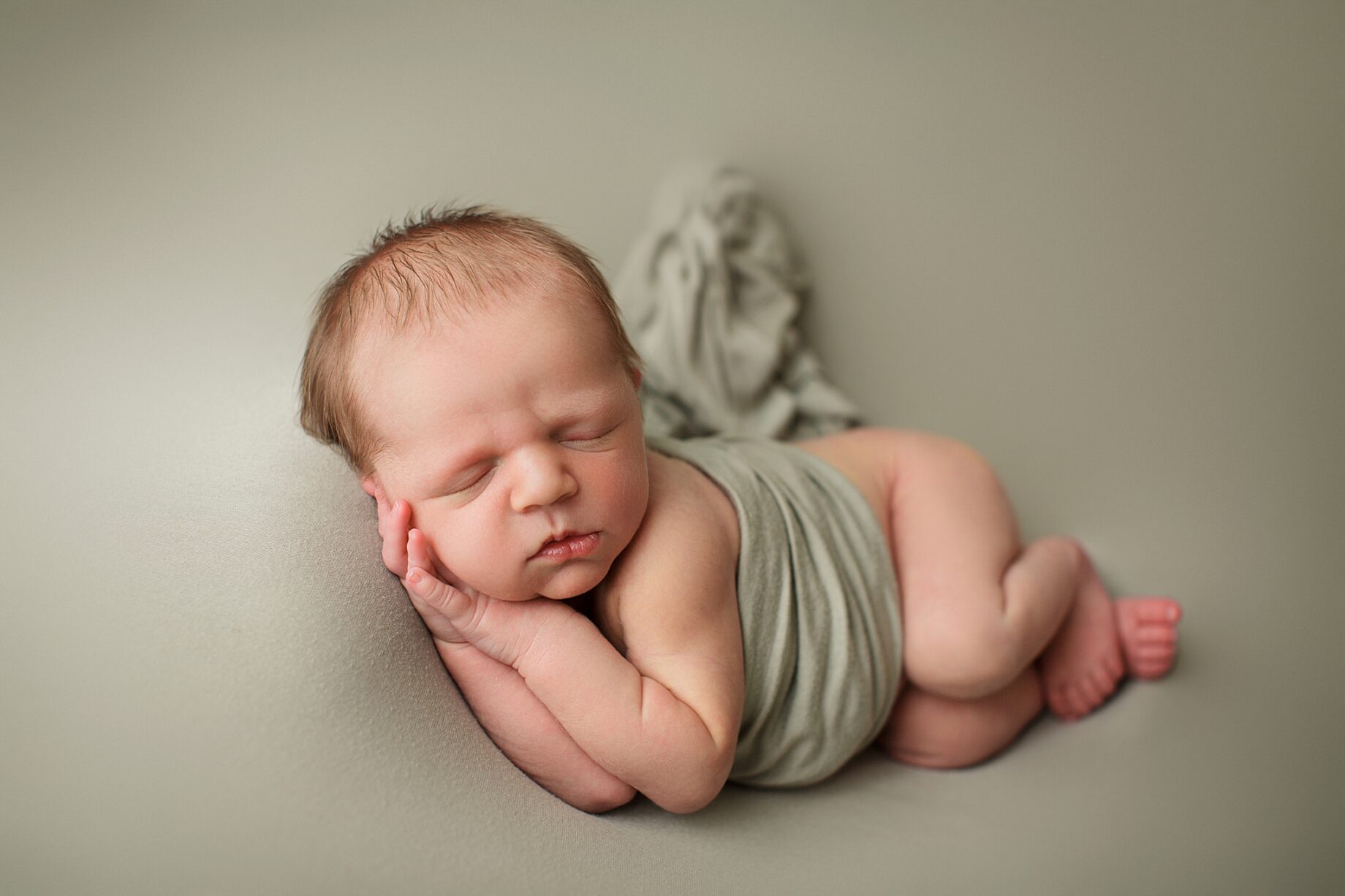 Farmington Missouri Newborn photographer, perryville newborn photographer, baby on green blanket, green backdrop, studio newborn photoshoot, baby sleeping, baby laying on side
