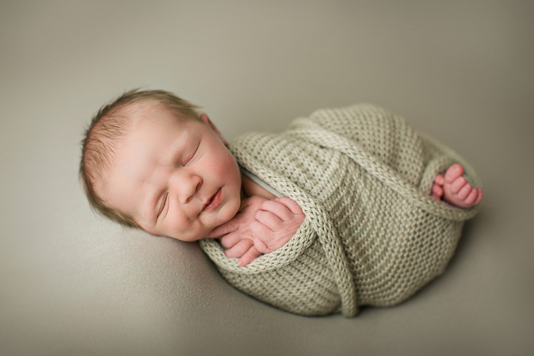 Farmington Missouri Newborn photographer, perryville newborn photographer, baby smiling, green blanket, swaddle, baby dimple
