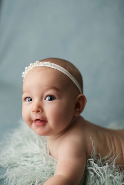 perryville newborn photographer, Cape Girardeau newborn photographer, blue backdrop, baby girl smiling, pearl tieback