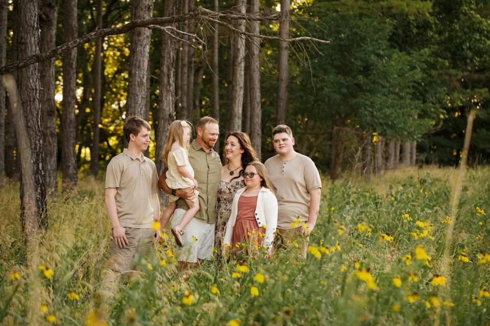 st Louis family photographer, Farmington Missouri Newborn photographer, flowers, tall pine trees, family looking at each other