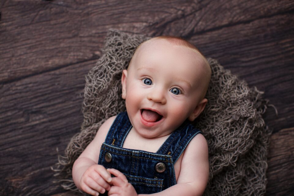 perryville missouri newborn photographer, st Louis newborn photographer, Cape Girardeau newborn photographer, farmington missouri newborn photographer, red head baby, 6 month photo session, bib overalls, dark wood floor, baby smiling, blue eyes