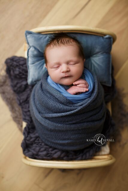 St. Louis newborn photographer, perryville Missouri Newborn photographer, farmington newborn photographer, wood floor, blue wrap, tiny bed, baby boy, folded hands