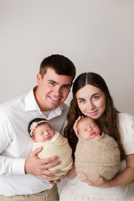 perryville newborn photographer, ste. Genevieve newborn photographer, baby sleeping, parents holding twins, white backdrop, studio photographer, newborn family photos