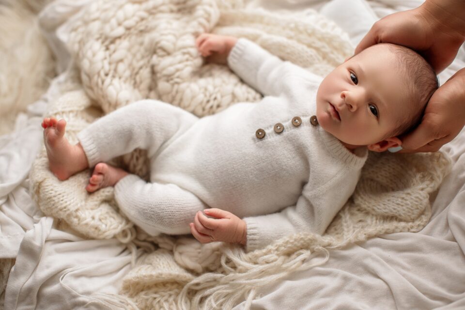 Cape Girardeau newborn photographer, perryville newborn photographer, baby on cream fuzzy rug, mom holding babies head, organic studio photos, newborn photo