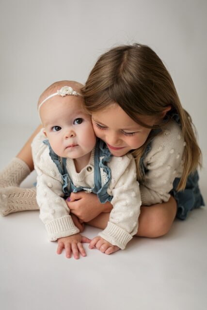 perryville newborn photographer, Cape Girardeau photographer, sisters, big sister hugging little sister, timeless photoshoot
