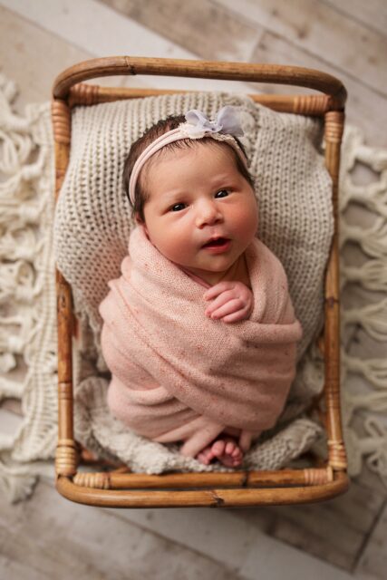 Cape Girardeau newborn photographer, perryville newborn photographer, baby looking at camera, newborn photo session, pink newborn setup, wood floor, studio newborn