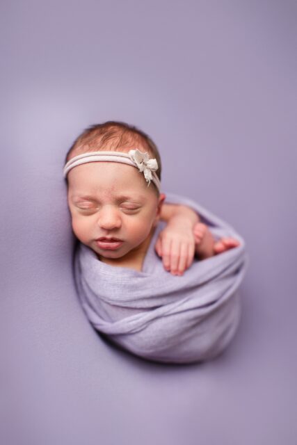 perryville Missouri Newborn photographer, st Louis newborn photographer, perryville Missouri Newborn photographer, Farmington Missouri Newborn photographer, purple backdrop, baby girl sleeping, studio lighting, purple bow