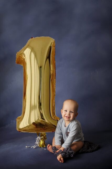 st Louis newborn photographer, farmington Missouri Newborn photographer, cape girardeau Missouri Newborn photographer, perryville first birthday photographer, baby holding 1 balloon, blue backdrop, little boy