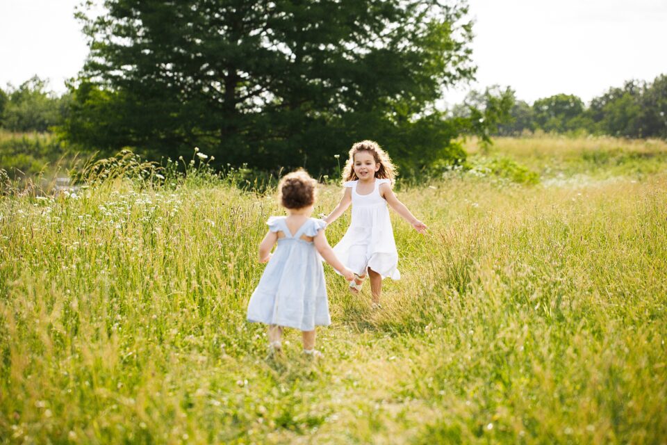 perryville Missouri Newborn photographer, st Louis newborn photographer, sisters, running in field, tall grass, girls in dresses