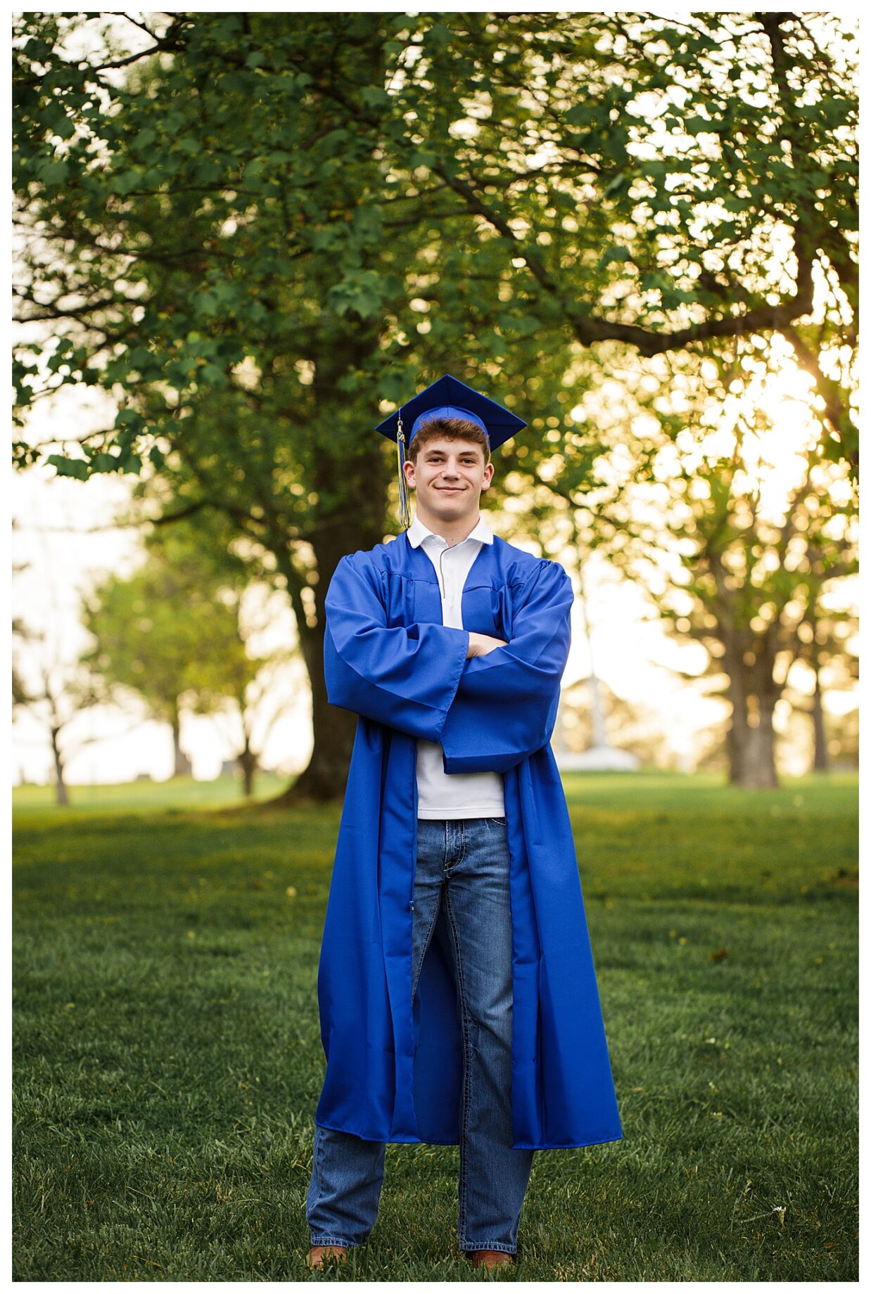 perryville missouri senior high school photographer, cape girardeau senior high school photographer, farmington missouri senior high school photographer, cape and gown, st Louis senior photographer, arms crossed, boy smiling, blue cap, field, green grass