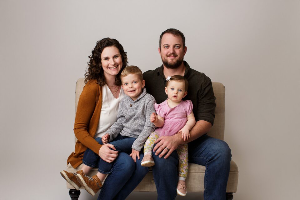 farmington Missouri Newborn photographer, st Louis Missouri Newborn photographer, family sitting on bench, smiling, first birthday photoshoot, neutral