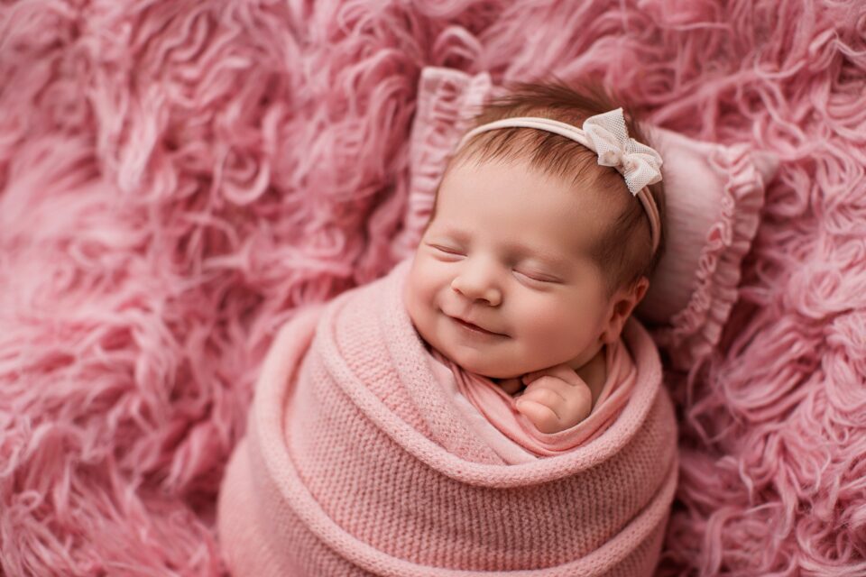 Perryville newborn photographer, Cape Girardeau newborn photographer, baby on fuzzy pink blanket, smiling